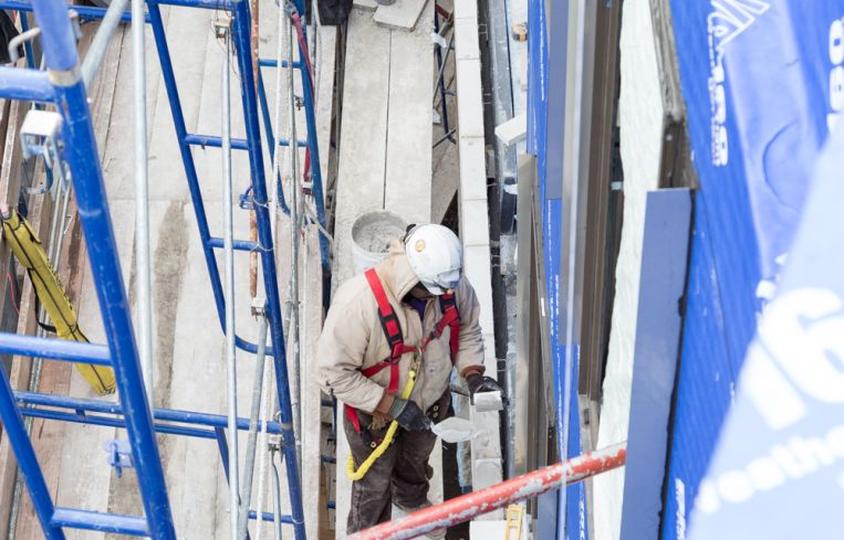 Masons install custom hand-made bricks onto the angled facade of a street-facing duplex townhouse unit.
Photo: Melissa Goodwin/For Commercial Observer