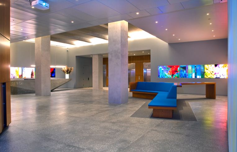 The former lobby of 315 Park Avenue South featured wooden furniture, concrete floors and gray walls and flashy artwork.