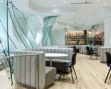 Frank Gehry's glass walls and curved seating originally designed for Condé Nast's cafeteria have been updated to a lighter color palette on the amenity floor at 4 Times Square.