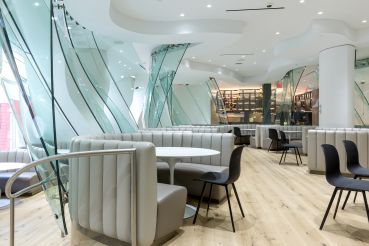 Frank Gehry's glass walls and curved seating originally designed for Condé Nast's cafeteria have been updated to a lighter color palette on the amenity floor at 4 Times Square.
