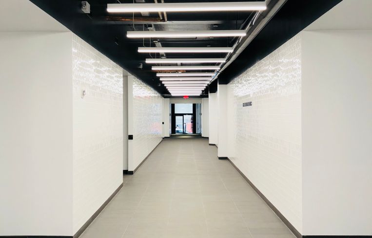 The newly renovated and extended corridor has white tiled walls and porcelain floors.
