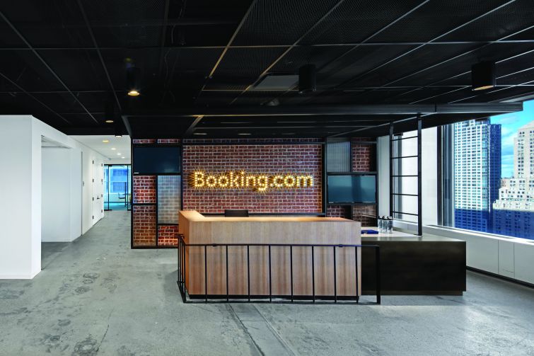 Booking.com's reception area has a lit up sign and a wood desk.