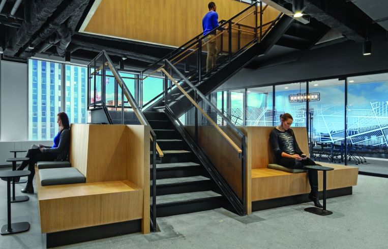 An open wooden and steel staircase connects the two floors of the 46,000-square-foot space