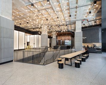 The large and open lobby of The Nomad Tower features a cafe, lots of daylight and an open staircase that leads down to the amenity level.