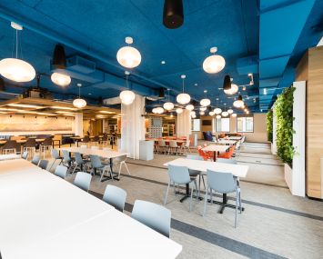 Macmillan's new offices include a full floor of common spaces, including a large cafeteria with plant walls and a variety of seating.