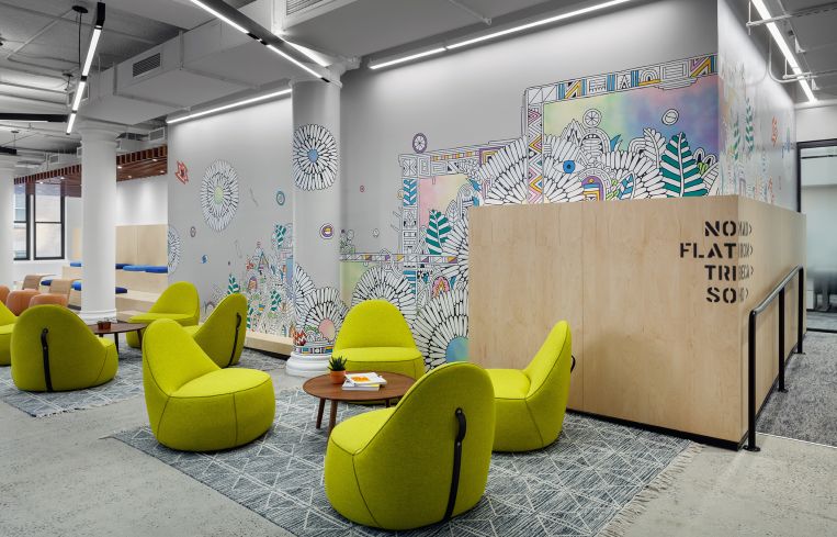 A colorful mural painted behind plywood is meant to be reminiscent of the city streets. Each part of the office is named after a city neighborhood, which is stenciled on walls or punched out of metal signs.