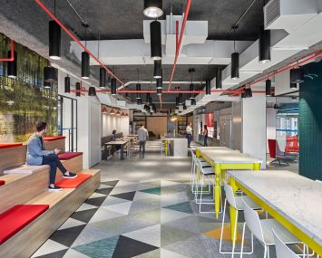 The kitchen, like many other parts of the office, has several splashes of primary colors, from the table legs to the cabinets and cushions.