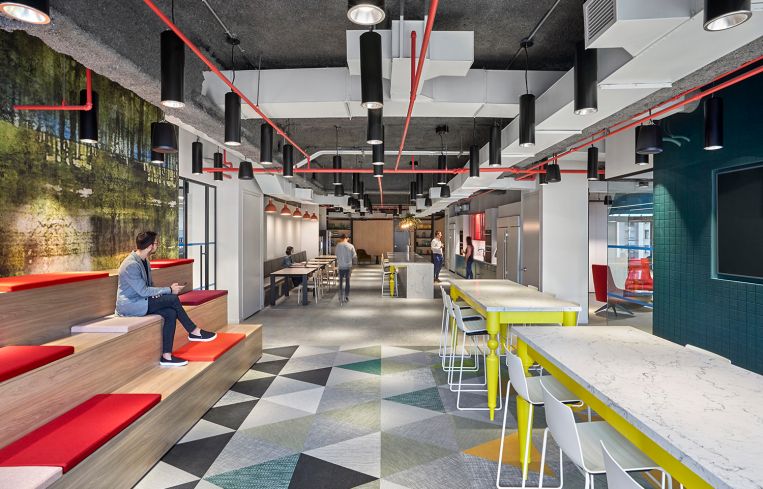 The kitchen, like many other parts of the office, has several splashes of primary colors, from the table legs to the cabinets and cushions.