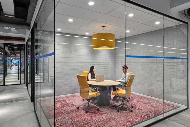 Yellow chairs and a light pendant help add interest to this conference room, which also has an overdyed rug.