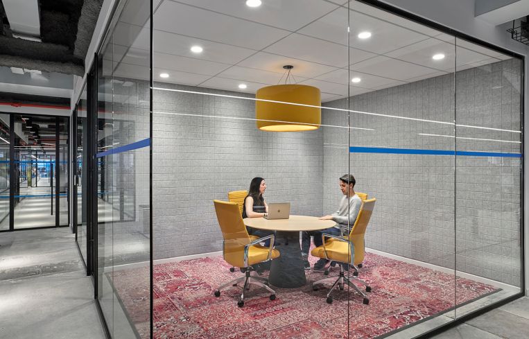 Yellow chairs and a light pendant help add interest to this conference room, which also has an overdyed rug.