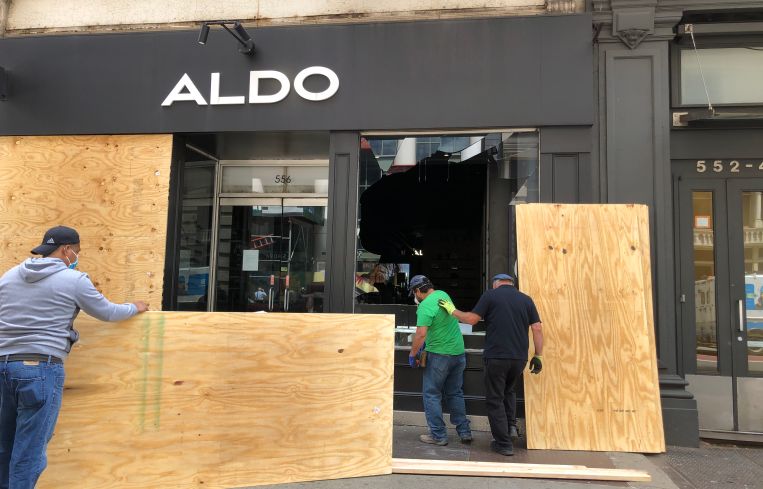 Workers board up a damaged Aldo store on Broadway in the wake of the May 31 George Floyd/Black Lives Matter protests.