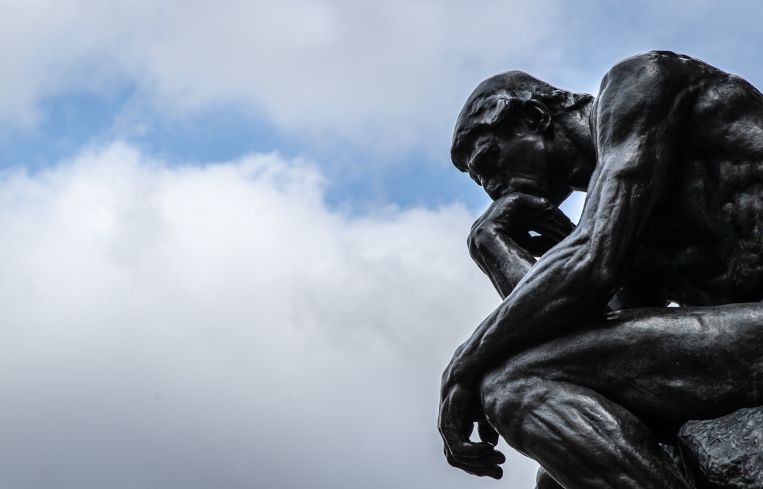 The sculpture "The Thinker" ("Le Penseur") by the sculptor Auguste Rodin can be seen against a cloudy sky.