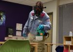 17th Civil Engineer Squadron pest controller Omar Martinez, walks around a classroom dispersing a disinfectant mist on all surfaces at Goodfellow Air Force Base, Texas, March 30. The chemical used is reportedly 99.99 percent effective at bonding to germs on the surface and killing them within the dwell time of 20 minutes. (U.S. Air Force photo by Senior Airman Seraiah Wolf)