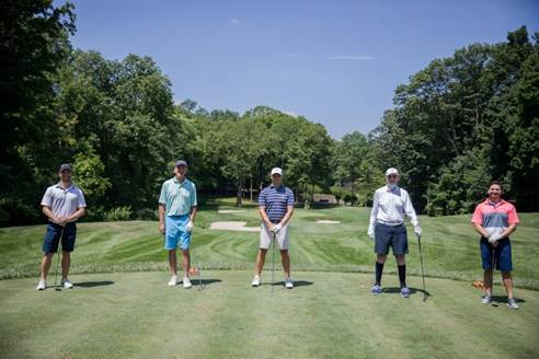 Five men on a golf course, spaced apart.