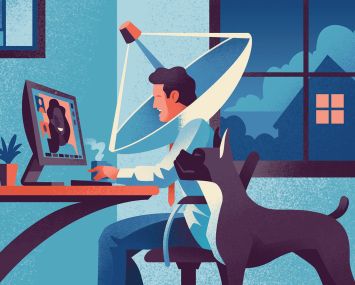 A man sitting at a desk with a dog next to him, and the man has a satellite dish around his head.