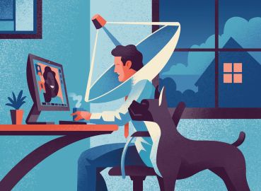 A man sitting at a desk with a dog next to him, and the man has a satellite dish around his head.