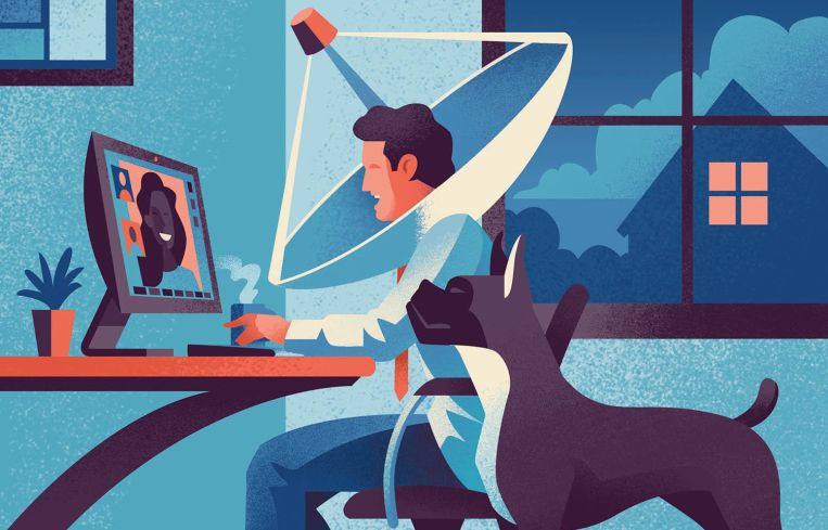 A man sitting at a desk with a dog next to him, and the man has a satellite dish around his head.