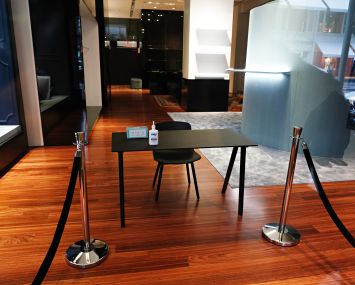 A table and a chair at the entrance of a sparse retail store.