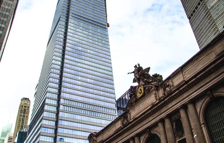 A glassy building viewed from far away on the street.