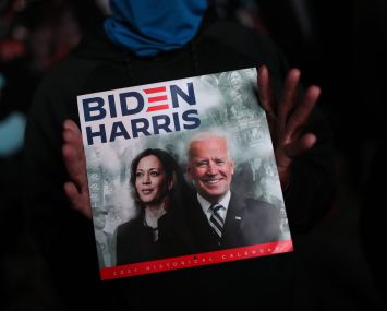 Two hands holding a sign that says Biden/Harris.
