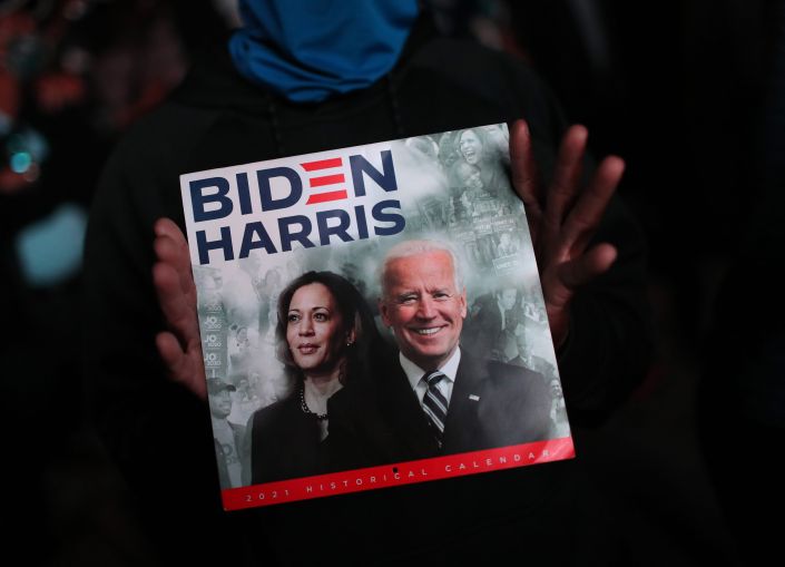 Two hands holding a sign that says Biden/Harris.