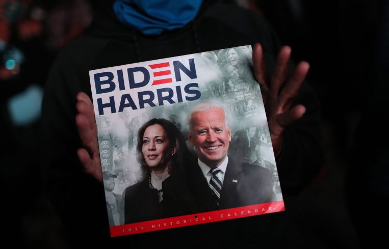 Two hands holding a sign that says Biden/Harris.