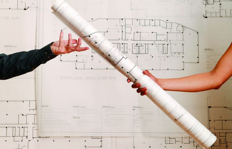 One arm handing off a rolled-up blueprint to another arm.