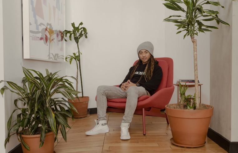 A young man sitting on a chair in a room.
