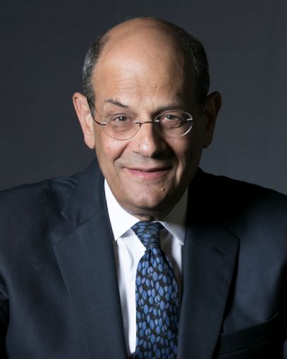 A man's headshot, and the man has glasses and is wearing a tie.