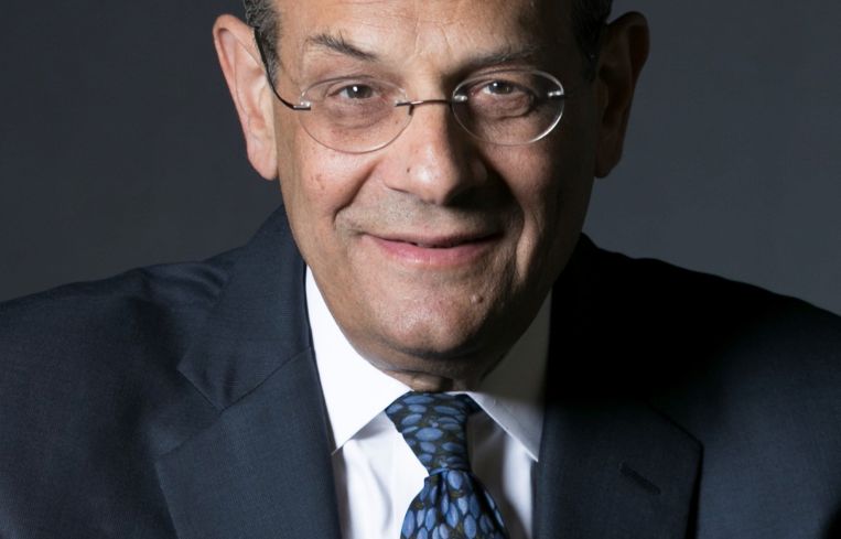 A man's headshot, and the man has glasses and is wearing a tie.