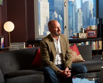 A man smiling and sitting on a couch in an office.