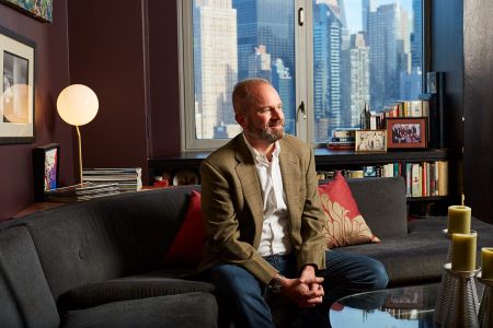 A man smiling and sitting on a couch in an office.