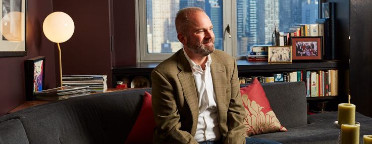 A man smiling and sitting on a couch in an office.