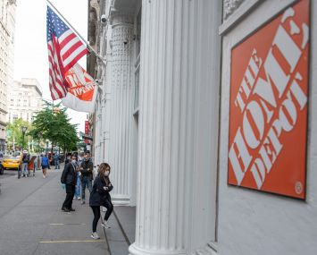 The outside of a store on a busy city street, and the outside has a sign that says "Home Depot."