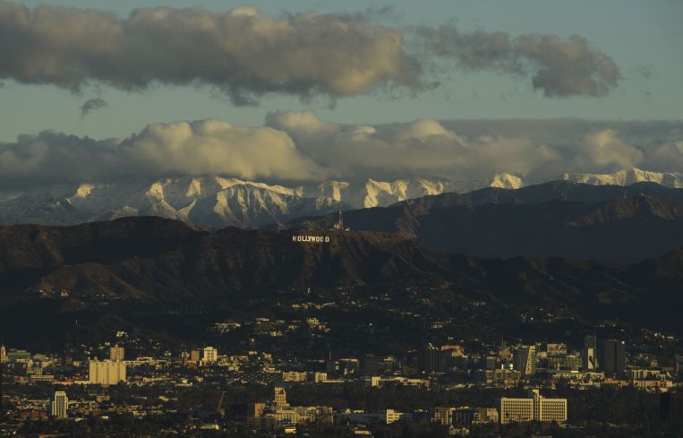 Snow-topped mountains stand behind the Hollywood Hills following heavy rains as seen from the Kenneth Hahn State Recreation Area on December 29.