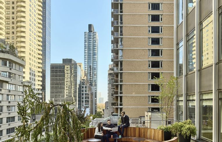 A large outdoor terrace has seating, planting and a raised platform for workout classes.