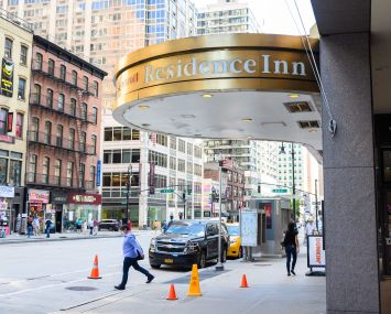 People walk outside the Residence Inn hotel by Marriott in midtown as New York City moves into Phase 3 of re-opening following restrictions imposed to curb the coronavirus pandemic on July 14, 2020 in New York City. Phase 3 permits the reopening of nail and tanning salons, tattoo parlors, spas and massages, dog runs and numerous other outdoor activities. Phase 3 is the third of four-phased stages designated by the state.