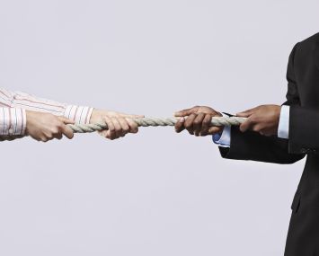 Two men pulling a rope from either side.