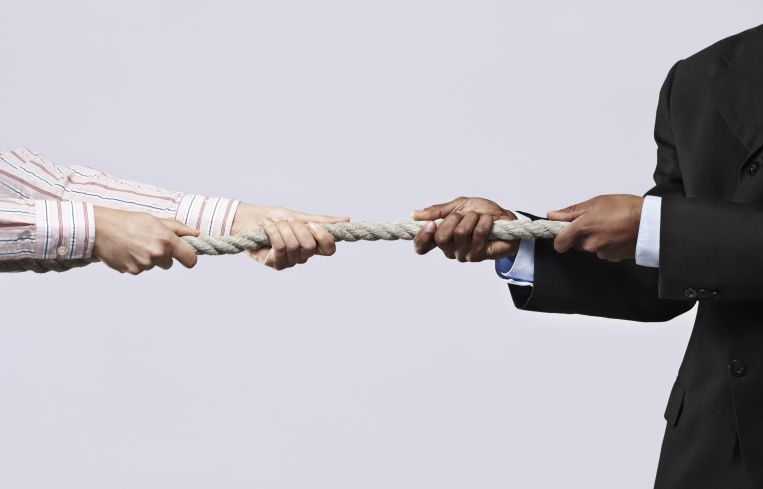 Two men pulling a rope from either side.