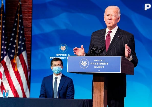 Two men, one standing at a podium and the other seated behind him.