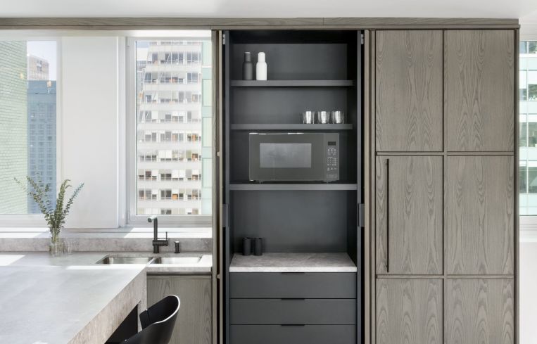 The space features a floor-to-ceiling wood cabinet that slides open to reveal an office pantry.
