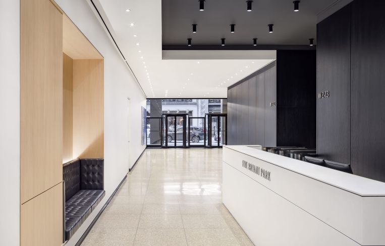 The renovation includes a new reception desk with a small wall seat on the opposite wall, as well as a series of paintings hung on the walls of the lobby.
