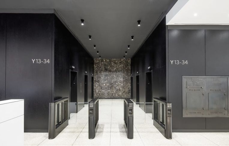 Black-stained wood panelling strikes a dramatic contrast for the ceiling and walls of the elevator banks.