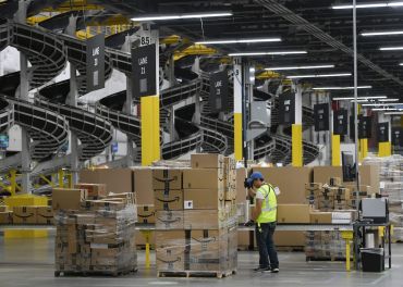 A warehouse associate wraps plastic around a pallet load of boxes at Amazon's fulfillment center. Demand has increased for industrial warehousing assets that support quicker supply chains, as well as supply chains that can move single items rather than large items or containers.