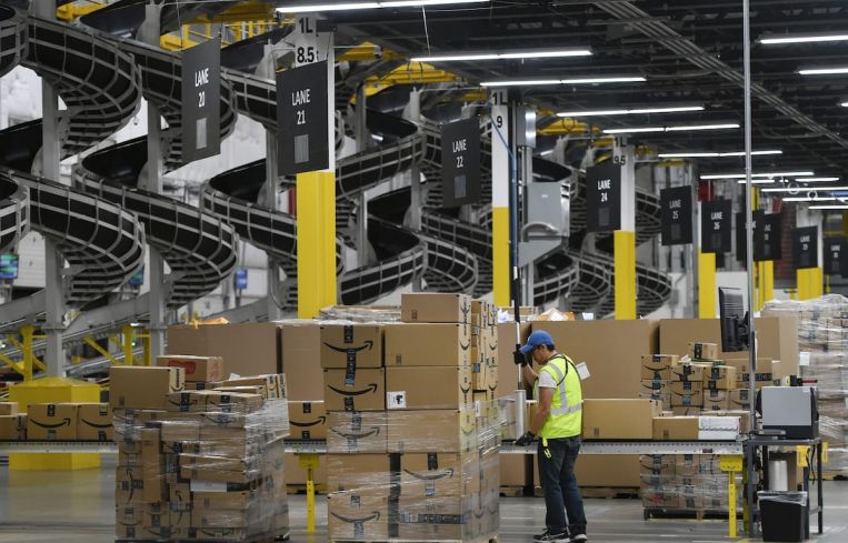 A warehouse associate wraps plastic around a pallet load of boxes at Amazon's fulfillment center. Demand has increased for industrial warehousing assets that support quicker supply chains, as well as supply chains that can move single items rather than large items or containers.