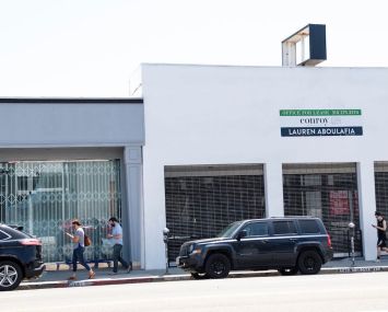 People wear masks as they walk by closed stores on the famous shopping area of Melrose avenue in Los Angeles amid the coronavirus pandemic.