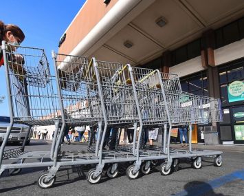 A Food 4 Less employee pushes carts past supermarket workers gathered to protest in front of the supermarket in Long Beach after a decision by Kroger to close two supermarkets rather than pay workers an additional $4 in "hazard pay."