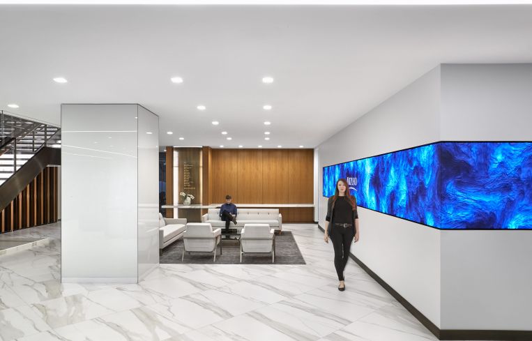 Common spaces include wood panelling, marble-like porcelain tile, and moving video walls.
