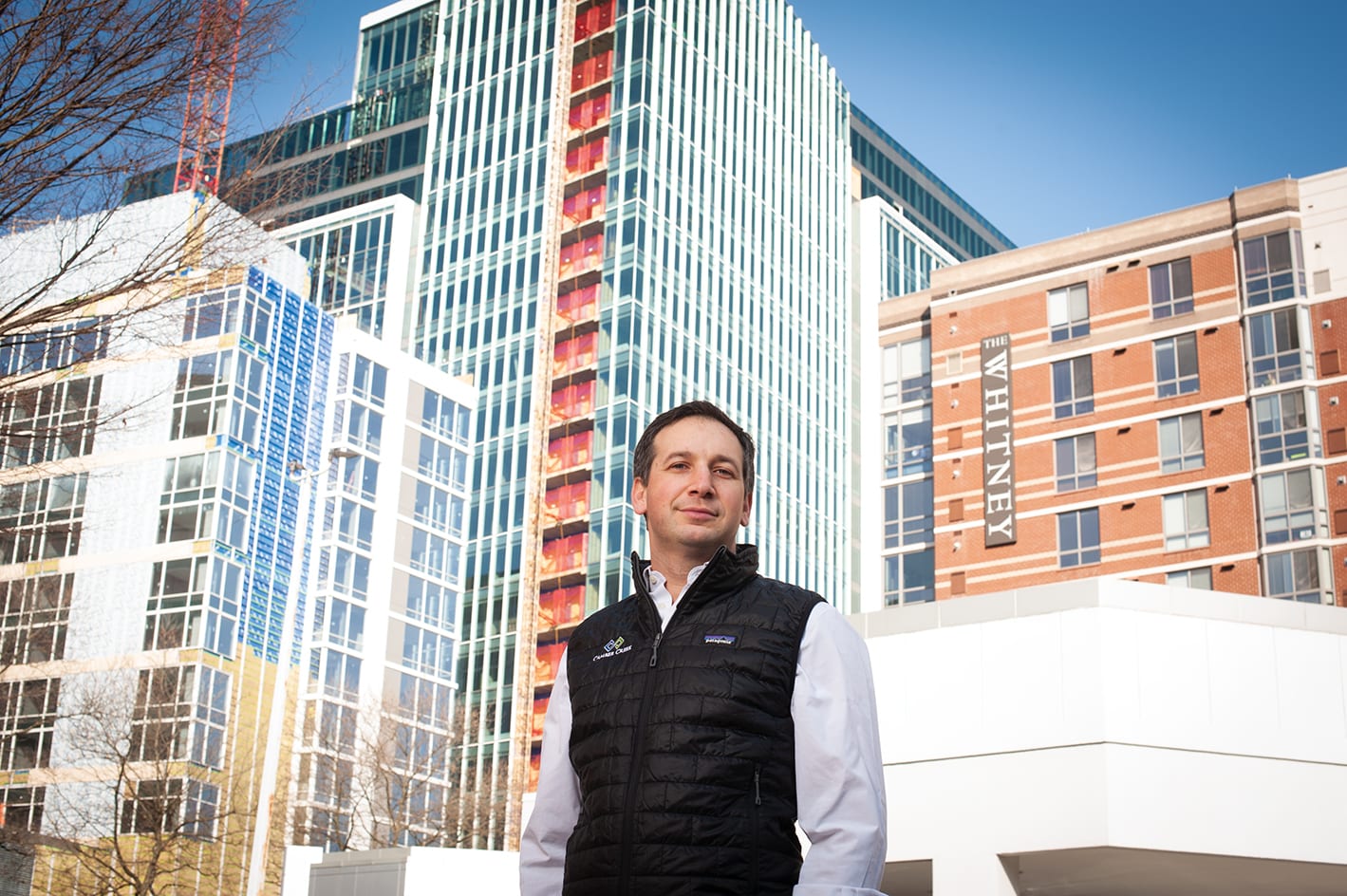 A man standing outside with buildings in the background.