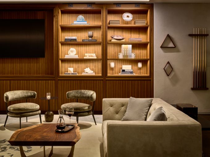 The "whiskey library" hosts shelving with nicknacks and books, along with gray and yellow midcentury couches and chairs and live edge coffee tables.  